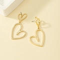Detailed close-up of gold hollow heart-shaped dangle earrings on minimalist background - Hollow Heart Style