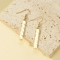 Golden long bar earrings with hammered texture and hook design on stone pedestal - Gold