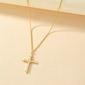 Elegante gouden kruisketting met parelinleg op een warme getextureerde achtergrond - Goud