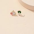 Vista detallada de pendientes asimétricos de cerdo y col sobre un fondo crema minimalista - Diseño asimétrico