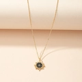 Golden sunburst starburst pendant necklace with black enamel center on curved surface - Gold