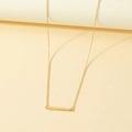 Minimalist gold bar pendant necklace with sleek geometric design on warm background - Gold