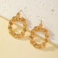 Dettaglio di orecchini a cerchio intrecciati dorati con texture a spirale su pietra bianca - Oro