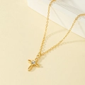 Elegante gouden kruishanger ketting met ronde zirkoon op een warme minimalistische achtergrond - Goud