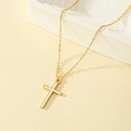 Polished gold cross pendant necklace with fine chain on minimalist display - Gold