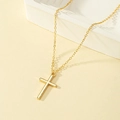 Collana minimalista con croce dorata e catenina sottile su elegante sfondo in pietra - Oro