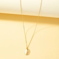 Collana minimalista dorata con ciondolo a conchiglia bicolore su sfondo beige - Oro