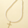 Elegante parelketting met een gouden kruishanger op een beige achtergrond - Parelkruis Stijl