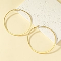 Grote gouden oorringen met een gekartelde textuur op een stijlvolle stenen ondergrond - Goud