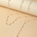 Elegant gold body chain necklace with pearls and a heart pendant on a creamy background - Pearl Back Chain
