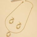 Elegante conjunto de joyas de flores doradas con perlas y cristales en fondo neutro - Conjunto de Perlas Florales Doradas