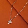 Collar con colgante de hoja de arce plateada y cadena sobre fondo de tela naranja - Oro Blanco