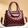 Close-up of wine red patent leather handbag with embossed checkered pattern and gold hardware - Red Plaid