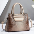 Detalle de textura de cocodrilo beige y herrajes dorados en el bolso de mano - Caqui