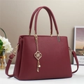 Elegante bolso de mano color burdeos en cuero con colgante floral dorado y correa ajustable - Rojo