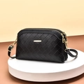 Women's black woven crossbody bag with dual zippers and gold accents on a display stand - Black