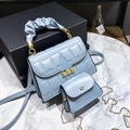 Close-up of light blue quilted handbag set with cloud handle and gold triangle buckle - Blue