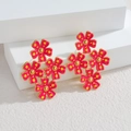 Retro 18k gold flower earrings with red enamel and yellow polka dots on a white stand - Red