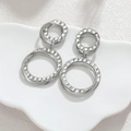 Pendientes de aro entrelazados de acero plateado con cristales en plato blanco - Color Acero