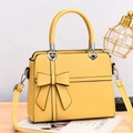 Large yellow faux leather shoulder bag with bow detail and heart buckles in lifestyle setting - Yellow