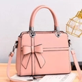 Detail of pink bow handbag featuring heart-shaped metal link and premium leather texture - Pink
