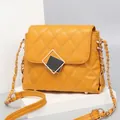 Quilted crossbody bag in mustard yellow with chain strap and gold hardware on pedestal - Small / Ginger Yellow