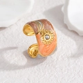 Macro detail of sunburst motif ring with orange marble enamel and white crystal inlay - Brown Orange