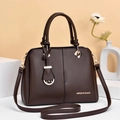 Close-up of dark brown lychee leather bag with gold hardware and logo detail - Brown