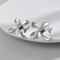 Orecchini a fiore d'argento con perla presentati su un piatto bianco con texture fine - Color Acciaio