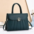 Detail of teal textured leather handbag featuring vertical pleats and golden metal buckle - Green