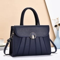 Detail of navy blue leather handbag with vertical pleats and golden round lock - Blue