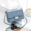 Sky blue quilted crossbody bag with gold rotating clasp and chain strap on white desk - Sky Blue