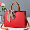 Detail of red faux leather tote bag with silk scarf accent and gold buckle closure - Wine Red