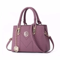 Dettaglio borsa a mano lilla in pelle martellata con logo dorato e ciondolo a catena - Viola