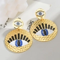 Detalle de pendientes de ojo turco dorados con acabado martillado y esmalte azulado - Pendientes de Ojo del Mal con textura martillada