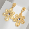 Elegantes pendientes de flor dorada con piedra púrpura sobre base geométrica blanca - Pendientes de flores grandes exagerados