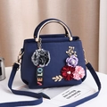 Elegant navy blue crossbody bag with 3D floral accents and golden hardware handles - Blue