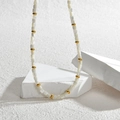 Bohemian style beaded necklace featuring white square beads and gold accents on stone props - White Beaded Necklace
