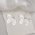 Orecchini pendenti a farfalla in argento traforato con ganci lunghi su tessuto bianco - Orecchini a farfalla traforata color acciaio