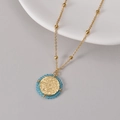 Collar dorado con colgante de moneda, relieve floral y detalle de cuentas azules - Dorado y Azul