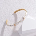 Detail of white enamel gold-plated cuff bracelet featuring colorful gemstone accents - White