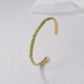 Golden open bangle featuring green enamel ribbing and colorful zircon gemstone accents - Green