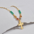 Vintage gold cross pendant necklace with colorful beads on a white stone background - Cross Style