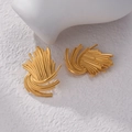 Pendientes dorados en forma de abanico con relieve de rayos sobre fondo de piedra blanca - Estilo de Rayo de Fuegos Artificiales Dorado