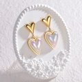Golden double heart earrings with shimmering opal effect on elegant white floral stand - Double Heart Iridescent Drop Earrings