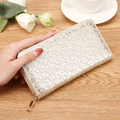 Long silver sequin wallet with leopard pattern and gold zipper in a lifestyle setting - Champagne