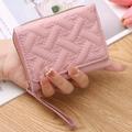 Pink quilted mini wallet with heart embroidery and wristlet strap held in hand - Pink