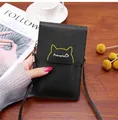 Nahaufnahme der schwarzen Crossbody-Handytasche aus Leder mit gelbem Katzenohr-Detail - Schwarz