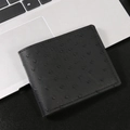 Men's bifold business wallet in black ostrich leather texture on a laptop keyboard - Black