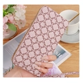 Pink monogram long zipper wallet with wristlet strap held over a coffee table - Pink